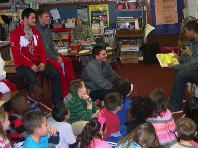 Football players reading to children.