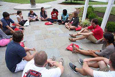 Students outside sitting in a circle discussing the summer reading selection