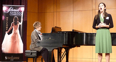 A pianist accompanies and young girl as she sings.