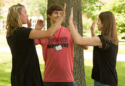 Three students particpate in a break-the-ice excercise at summer orientation.