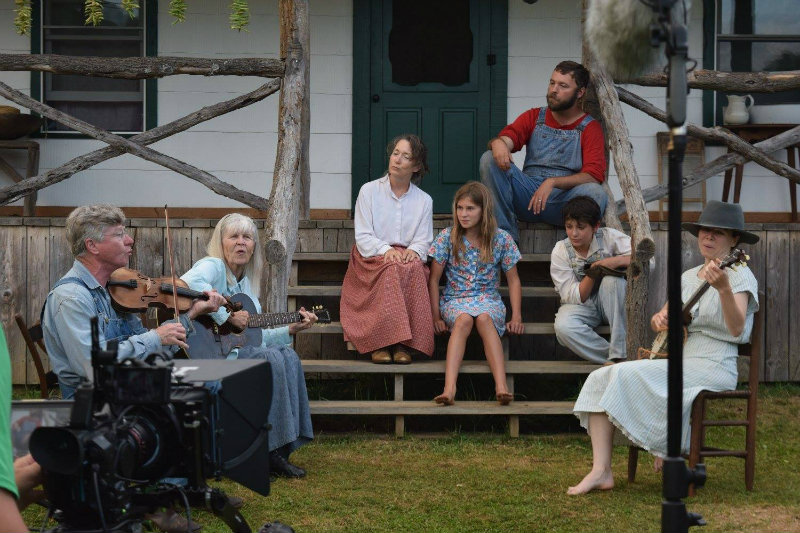In a scene from 'The Mountain Minor' film, Warren and Judy Waldron (left) play music as Amy Cogan Clay and Jonathan Bradshaw, seated on porch, and others watch.