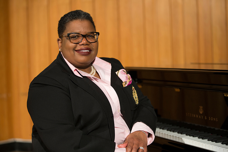 Tammy Kernodle turns toward the camera as she sits at a piano