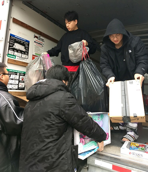 Four international students unload toys from the back of a truck