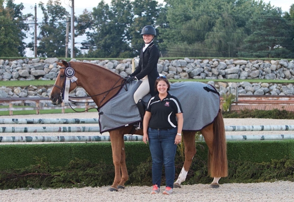 maggie niessen sits on a horse and heather pinnick stands next to the horse