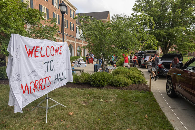 Welcome to Morris Hall bed sheet banner hangs on a stand as student move into their residence hall