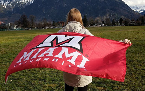 woman holds a miami flag looking at a mountain