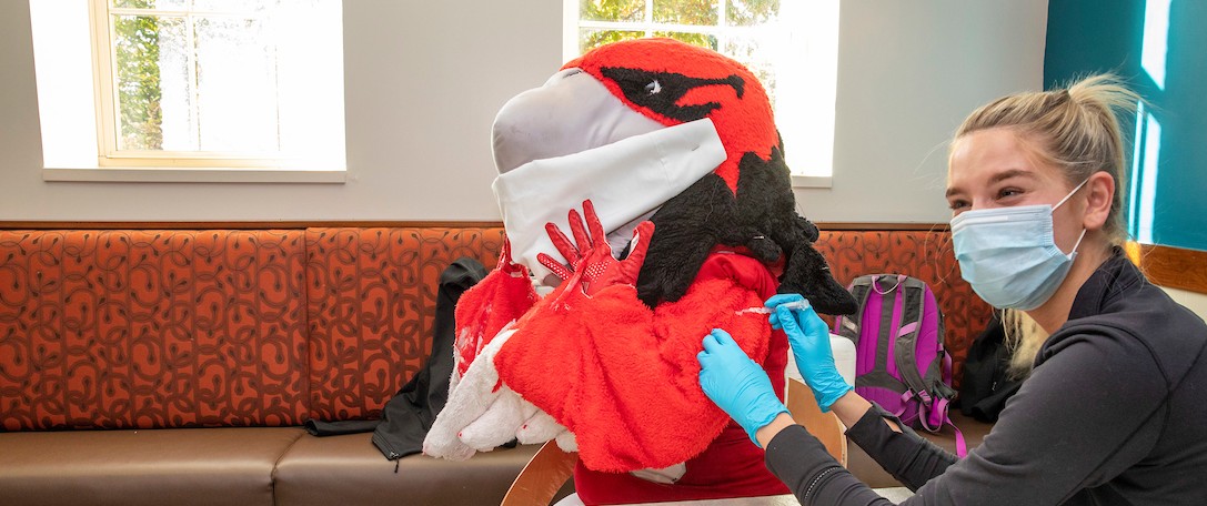 Mascot Swoop getting the vaccine from a Miami nursing student