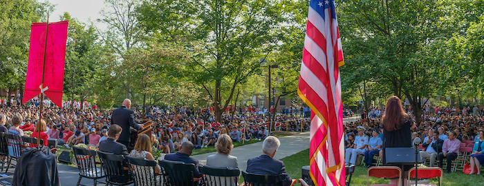 2017's incoming class sitting on the grassy lawn, listening to President Crawford give a speech