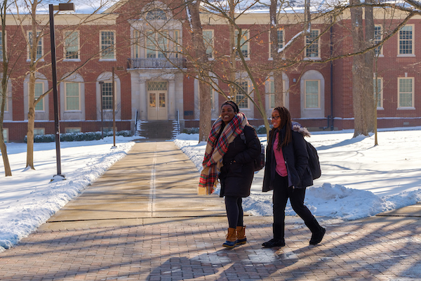 Two students walking to class while the campus is blanketed in snow.