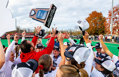 Field hockey team celebrating with the MAC championship trophy