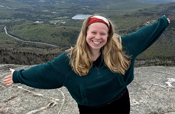 Chloe Waddle standing on a cliff that overlooks a large forested area
