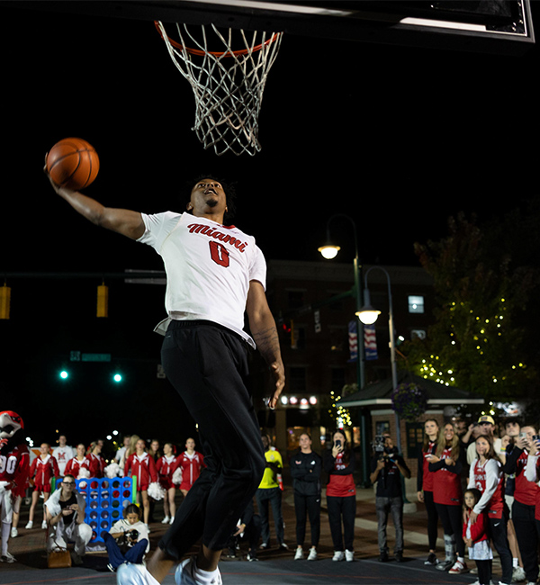 a basketball player making a layup on an uptown basketball court with a crowd watching