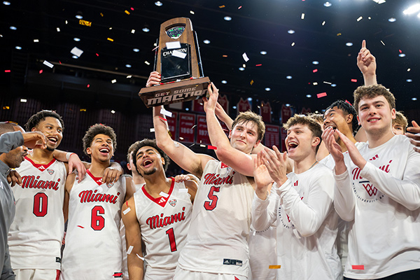 Men's basketball team holding up their Mac championship trophy