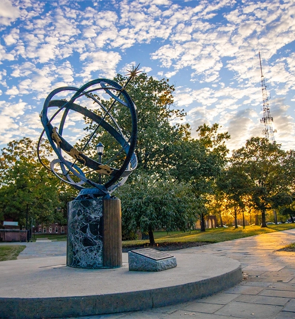 the sundial with a blue sky and spots of white clouds behind it