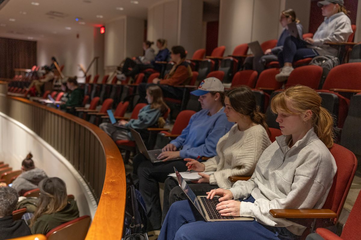 Students seated in a lecture hall working on computers.