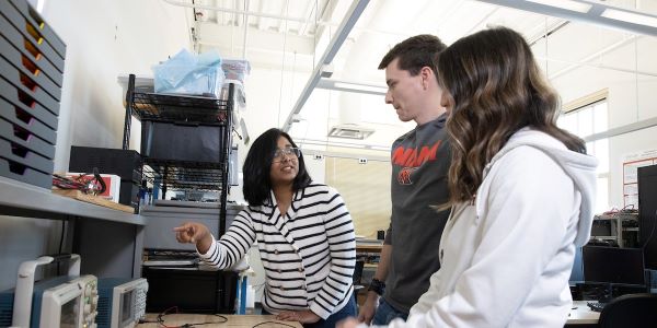 Professor doing research with 2 students in an engineering lab