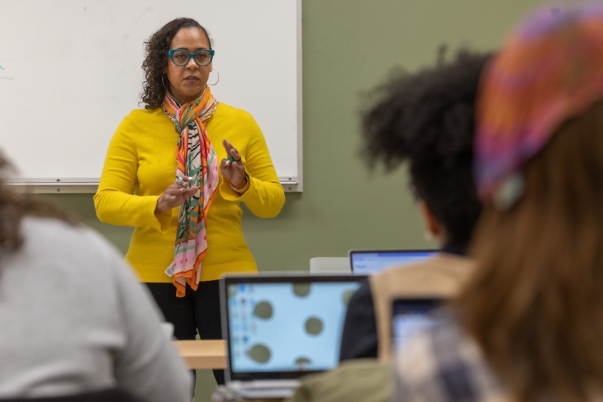 Professor Stephanie Dunning teaching near a whiteboard to her class of students using laptops
