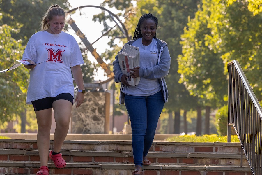 Two female students walking down the steps by the sundial