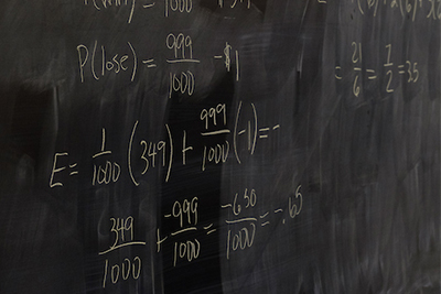 Chalkboard filled with mathematical equations and calculations, showcasing probability and expected value.