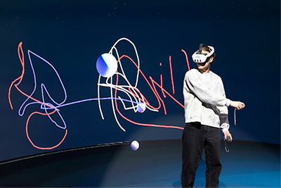 A person wearing a virtual reality headset interacts with colorful, abstract digital elements in a virtual space.