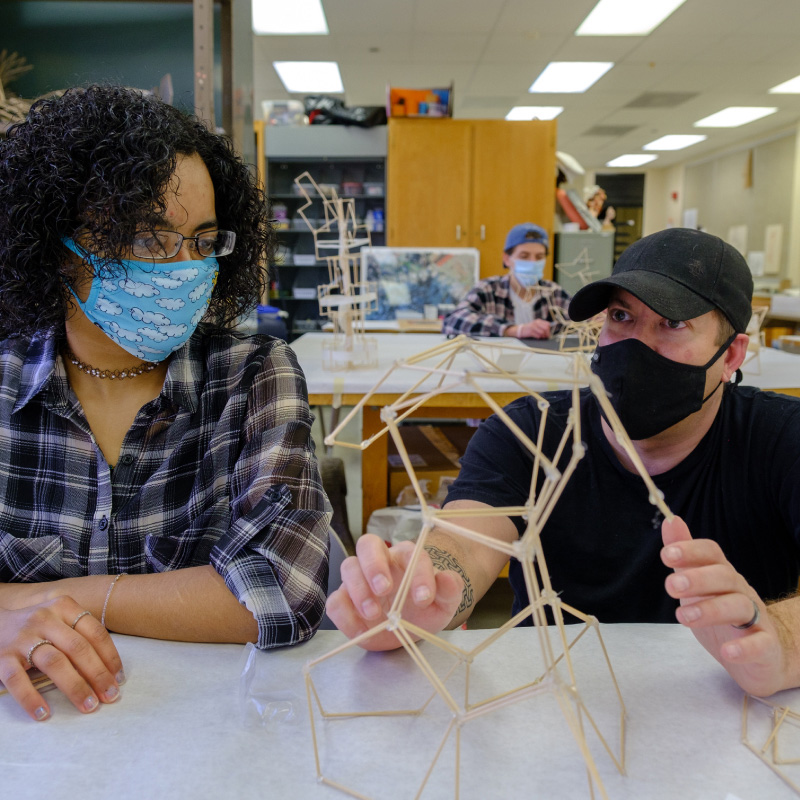 Miami Regionals students building a hexagonal sculpture out of wooden sticks.