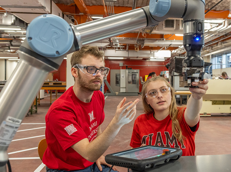 Miami Regionals students working with a robotic arm on a machine