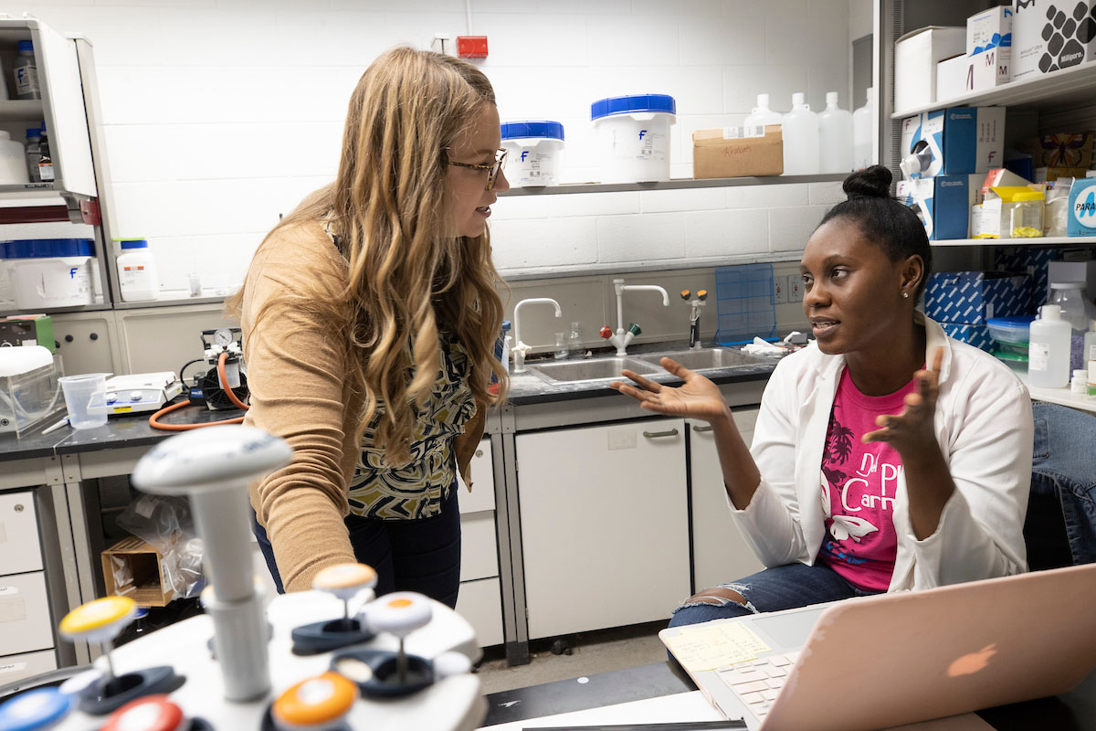 A biochemistry student and professor having a discussion in a research lab