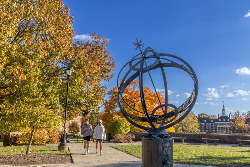 Students walk in front of the sundial in front of MacCracken Hall on a sunny fall day at Miami University's Oxford campus.