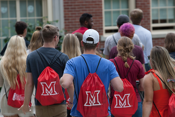 New students visiting Miami wear red satchels while touring campus