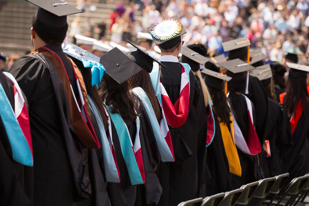 Students lined up to graduate wearing commencement robes and caps