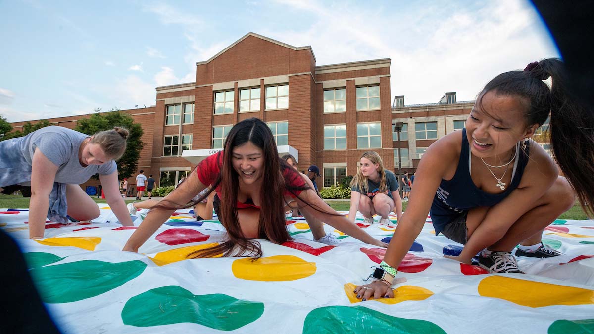 Students playing the game Twister in the grassy quad
