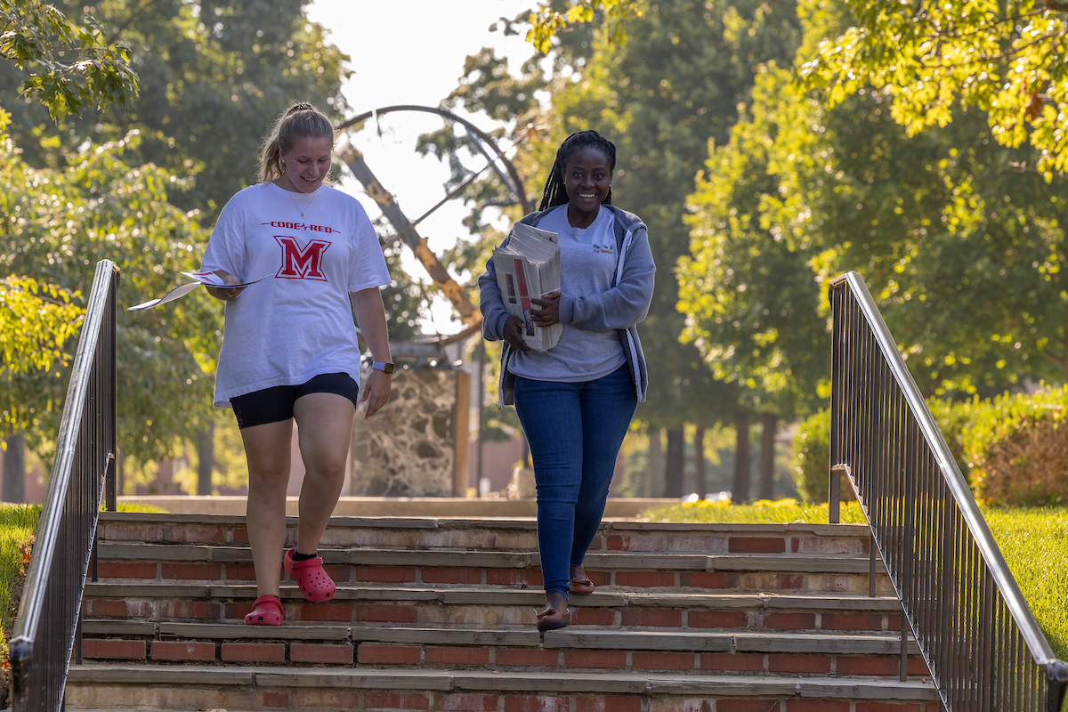 Two female students walking down the stairs by the sundial