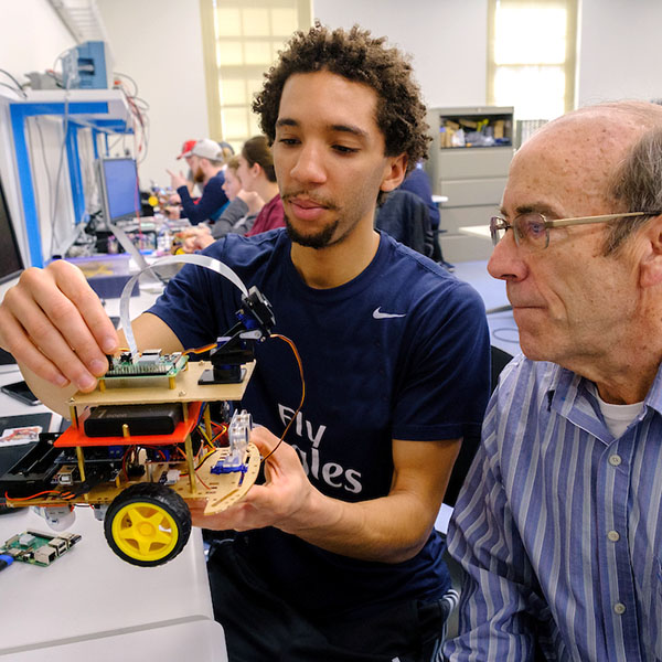 A professor helping a student with a robotic vehicle