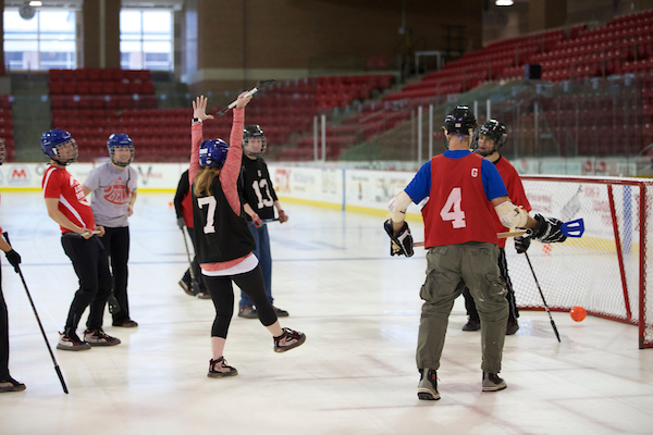 A co-ed game of broom ball. A student is cheering because she just scored a goal.