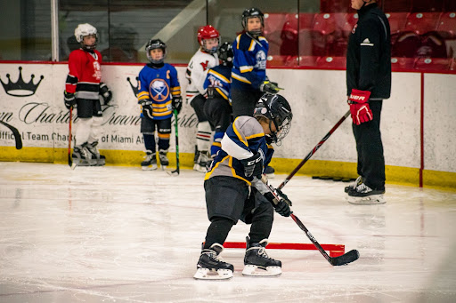 a child skating through obstacles on ice while dribbling a puck 