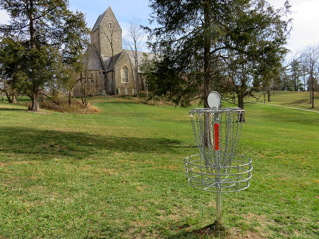 Disc golf basket in front of the Kumler Chapel