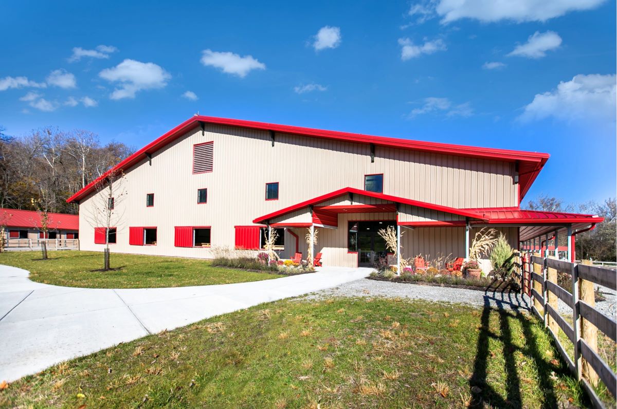 Exterior view of the indoor arena with red roof and trim