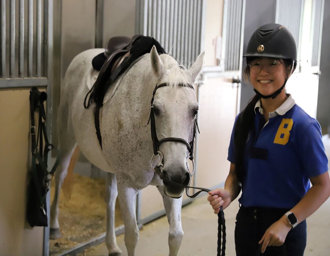Youth team member leading a horse out of a stall