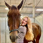 Isabel Tuckett hugging her horse in the barn