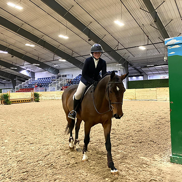 Kelsey Giorgio riding a horse in an indoor arena