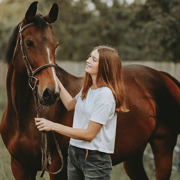 Roberta Cullinan standing next to her horse and petting its head