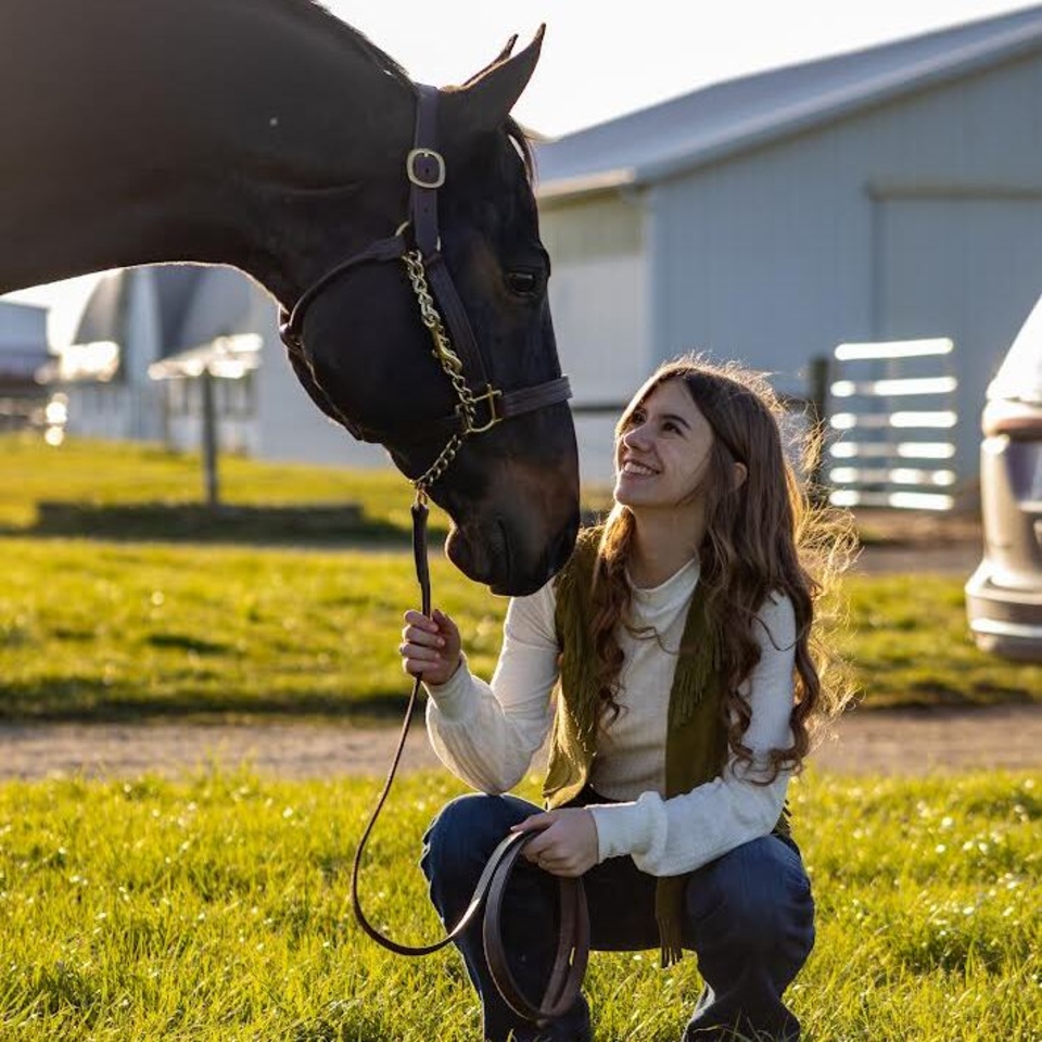 Vicki Brandi squatting beside horse