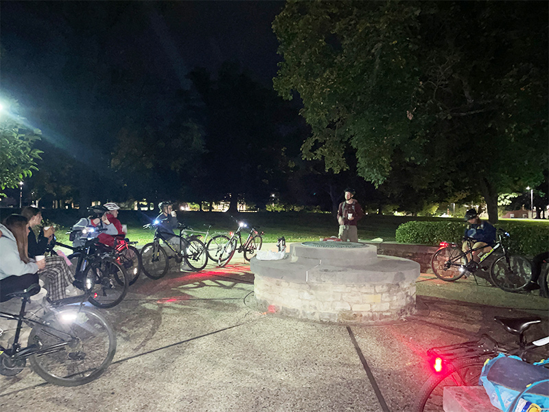 students gathers on campus at night with for ghost and gears bike tour