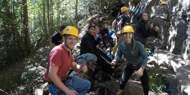 Students wearing helmets and harnesses for their climbing adventure