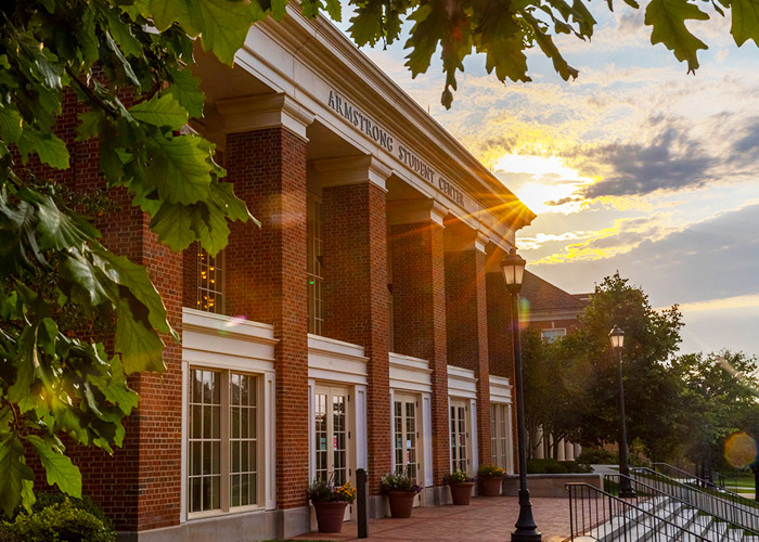 a view of the front of armstrong student center as the sun in going down behind it