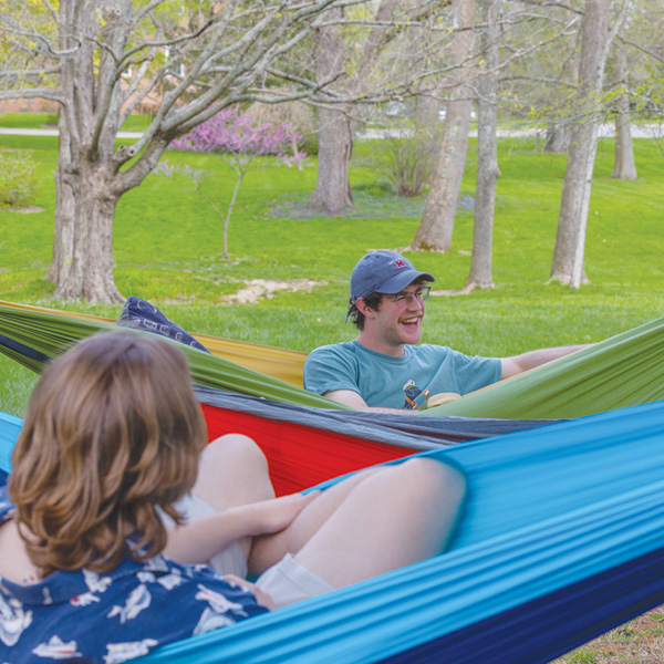 three students lounging in hammocks in a quad
