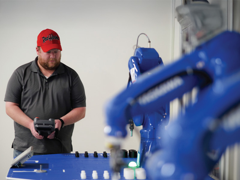 A student using a remote to control a blue robot