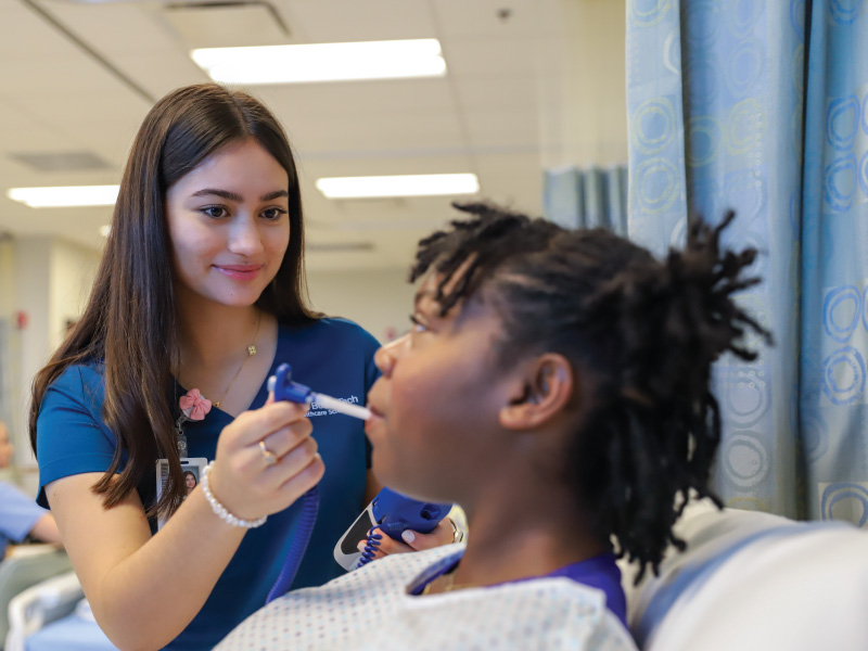 Butler tech nursing student place a thermometer in the mouth of a patient to check her temperature.
