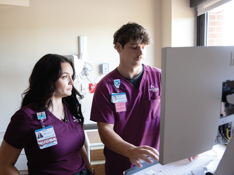 Miami Nursing student working at Kettering Hospital on a computer with his supervisor. 