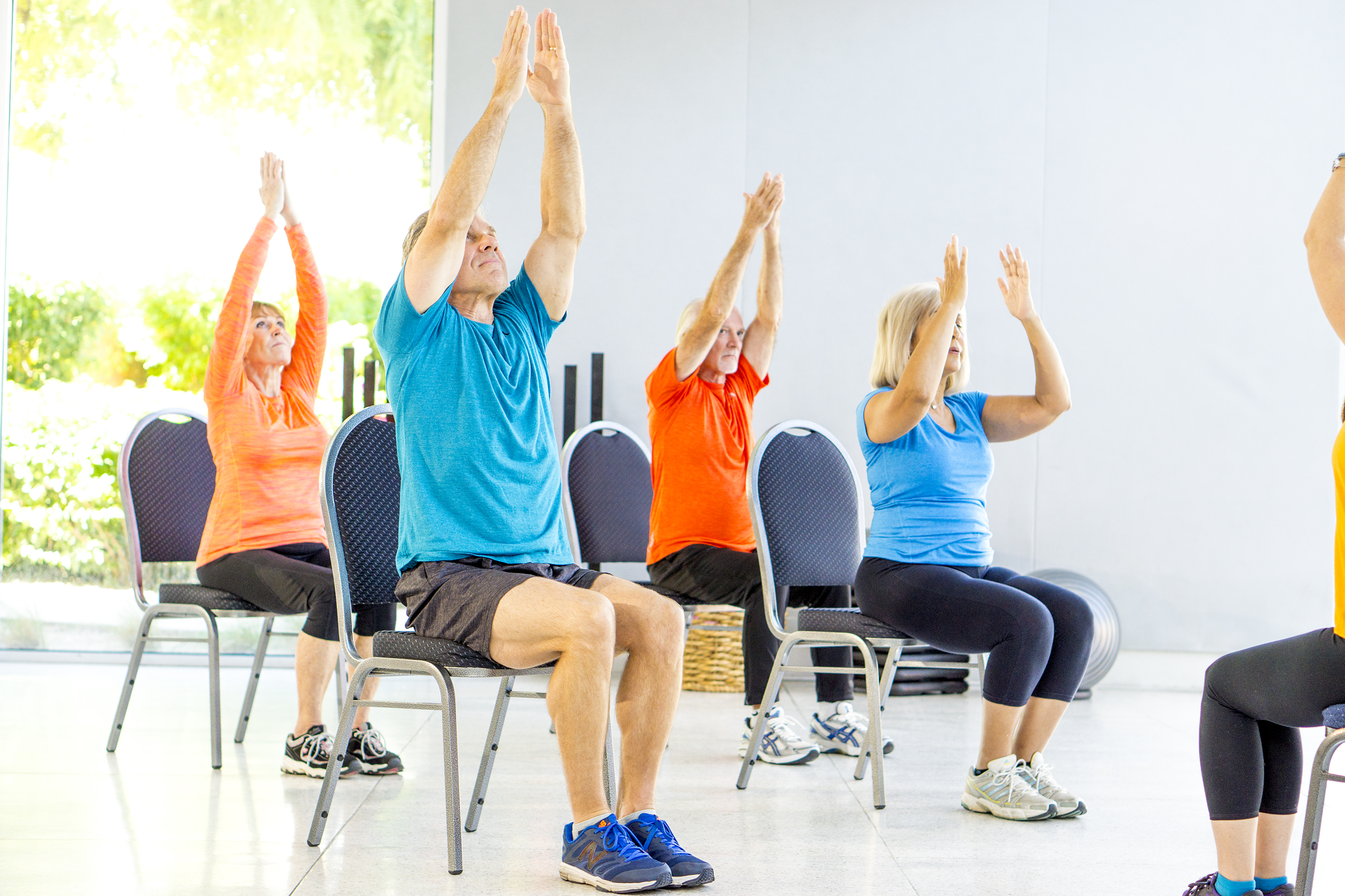 Older adults participate in a seated yoga class.